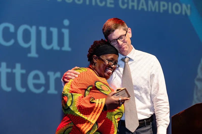 John Farrell (right) embraces Corporate Accountability and Energy Justice Champion Jacqui Patterson at ILSR’s 50th Anniversary Gala on May 01, 2024. Photo credit: Ruby Ella.